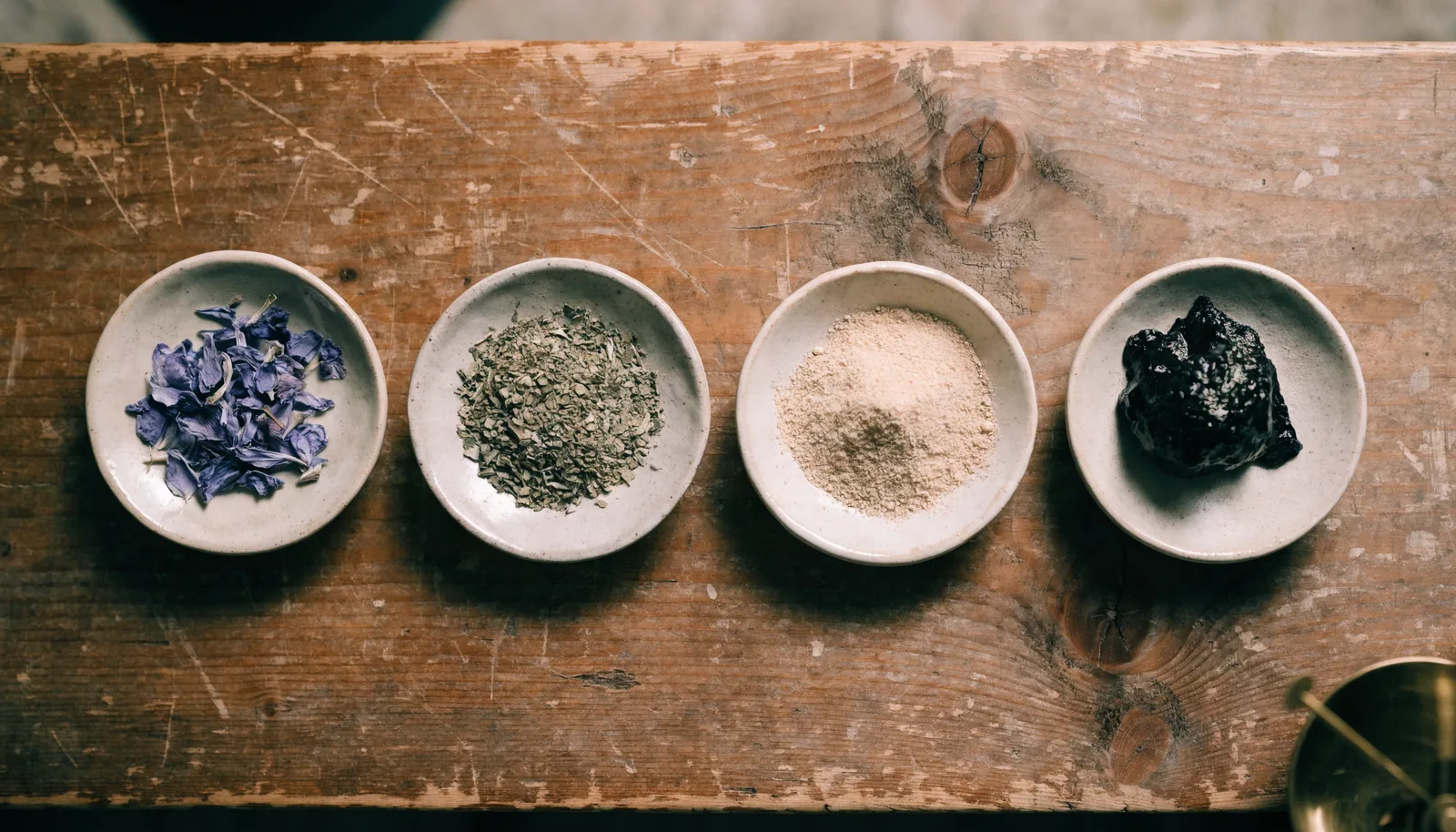 Coupelles en céramique montrant des pétales de lotus bleu, du kanna séché, de la poudre d'extrait et de la résine
